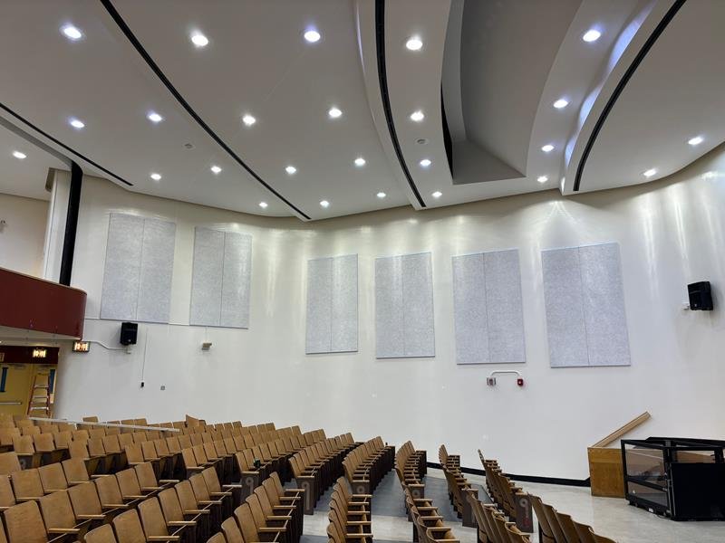 Auditorium with acoustic wall panels, curved ceiling coves and recessed lighting