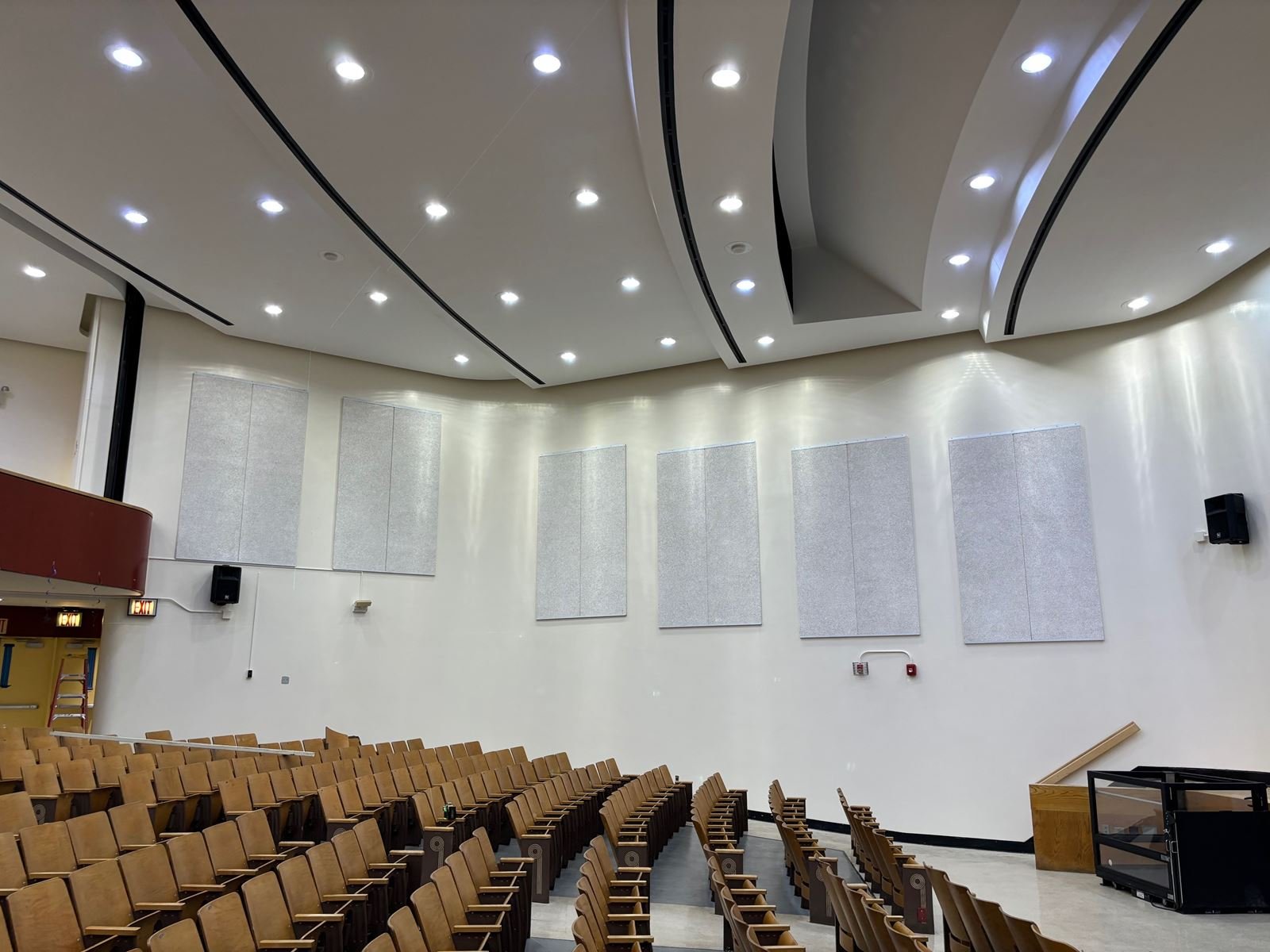 School auditorium with new acoustic wall panels, curved ceiling coves and recessed lighting