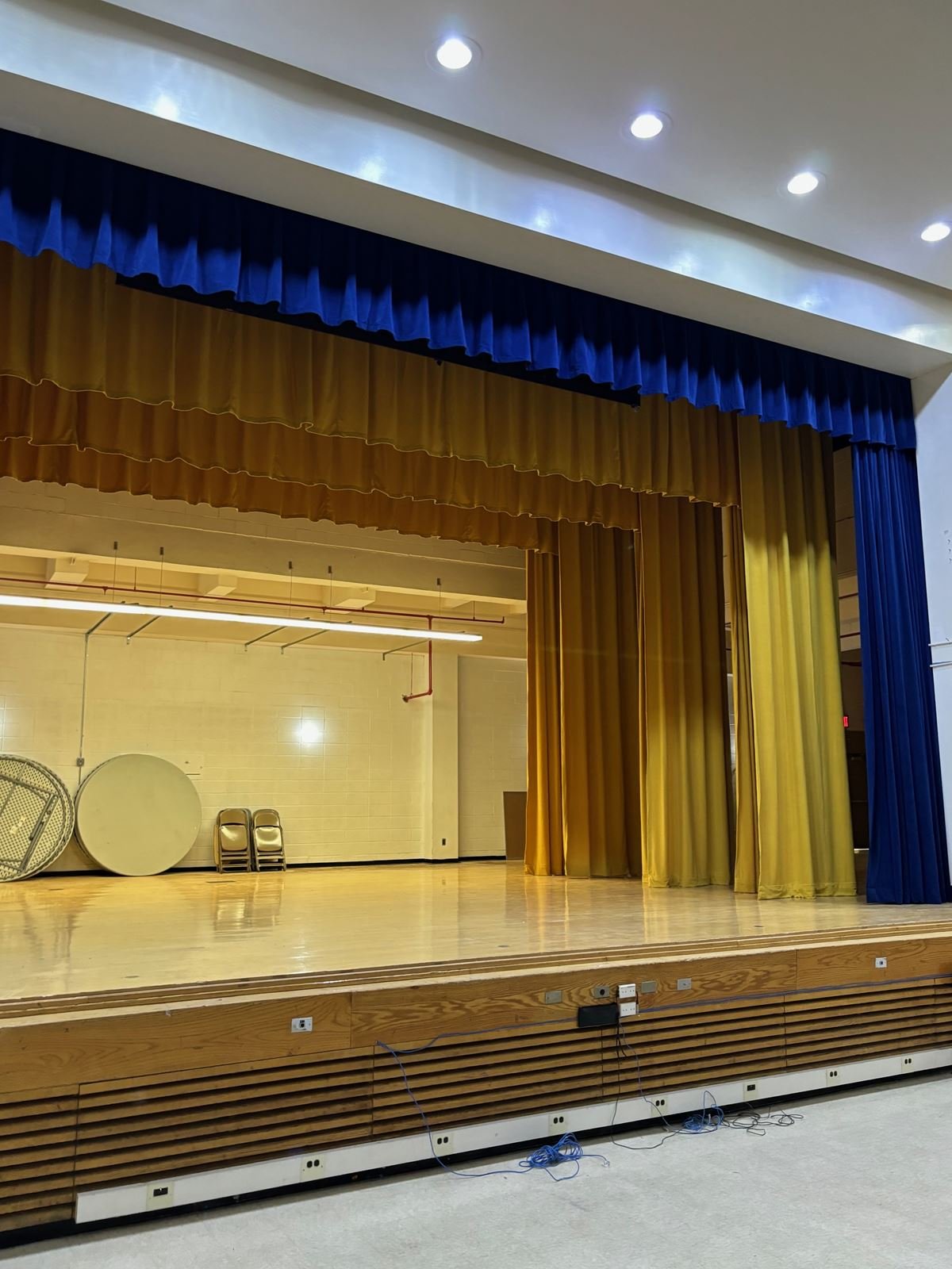 School auditorium stage with new blue and gold curtains and refinished stage floor