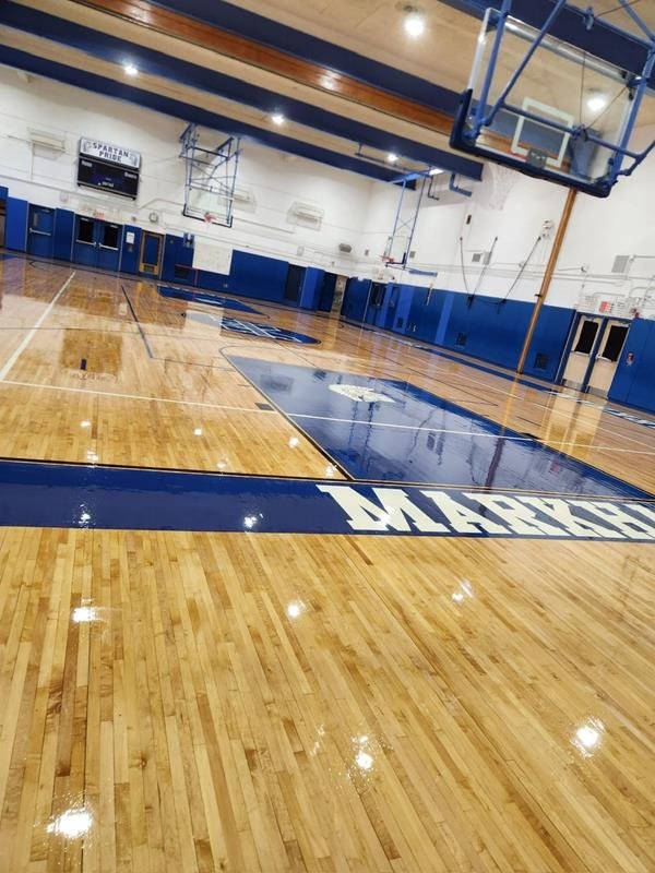 Glossy refinished gymnasium floor with navy key and blue wall padding