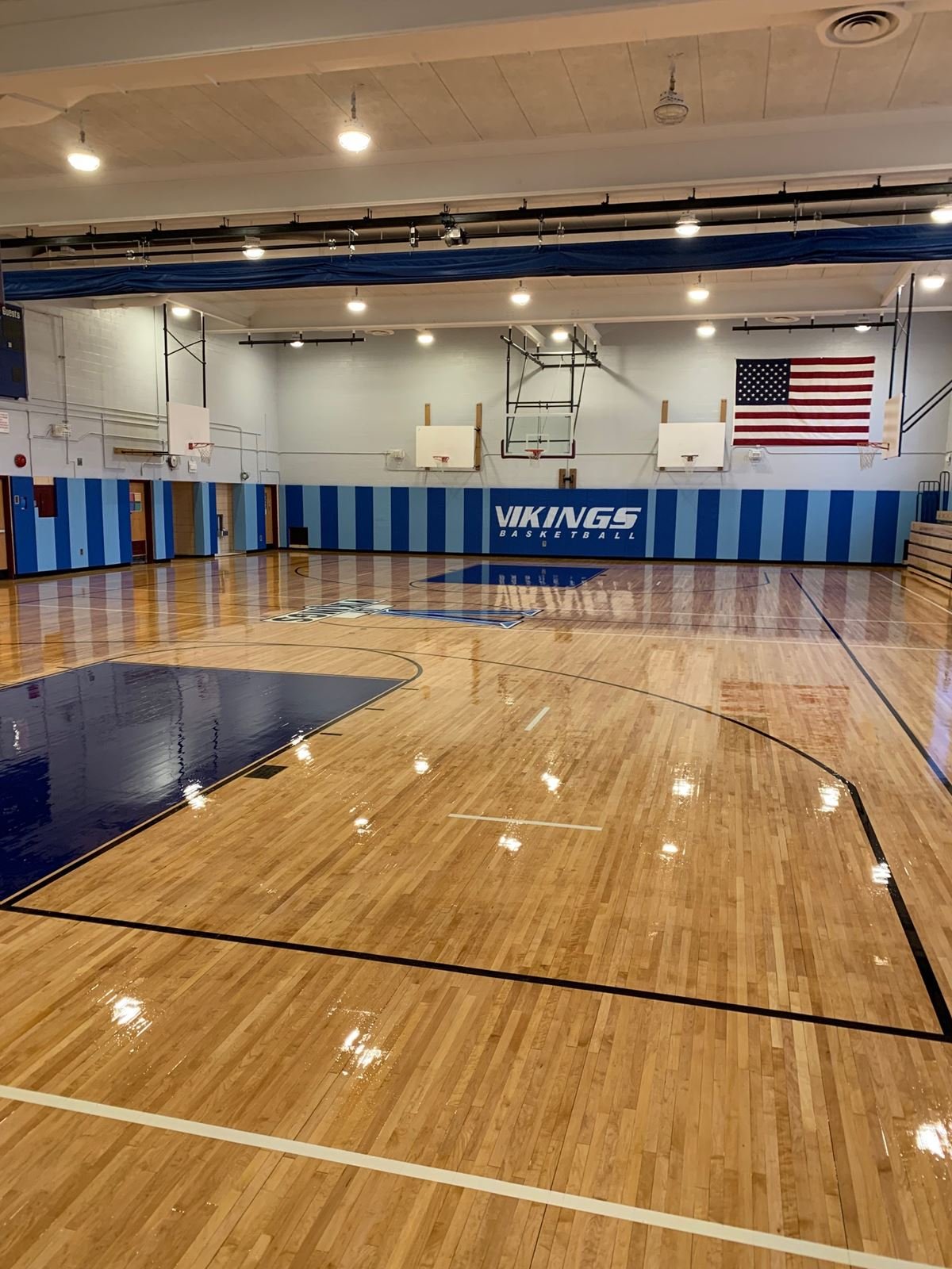 Refinished hardwood gymnasium floor with new game lines and wall padding at I.S. 7 on Staten Island