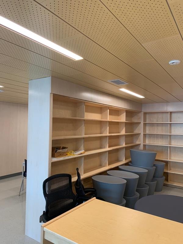 Library fit-out with maple shelving, stacked stools and wood ceiling